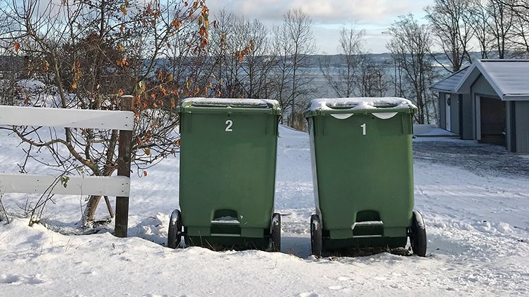 Två sopkärl står i snön.