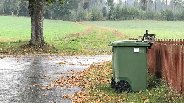 Sopkarl framför ett rött trästaket.