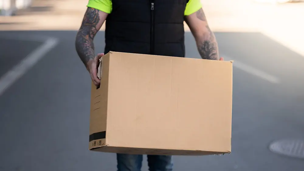 En person bär en flyttkartong.