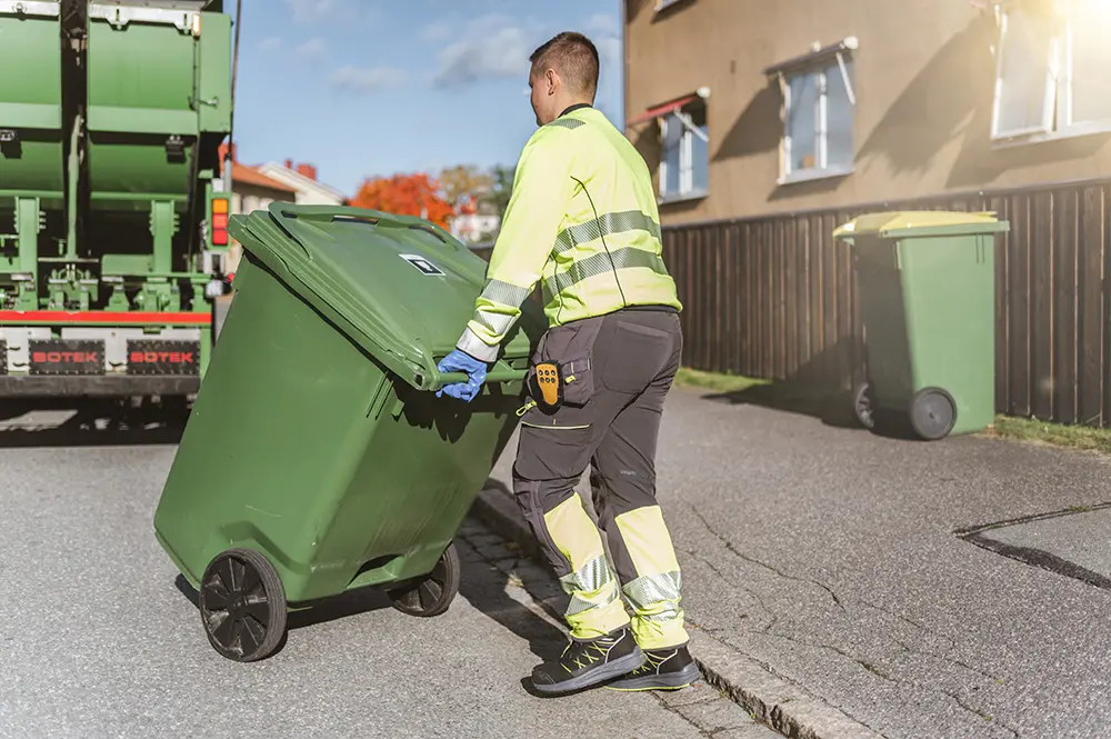 En chaufför kör ett kärl till sopbilen.