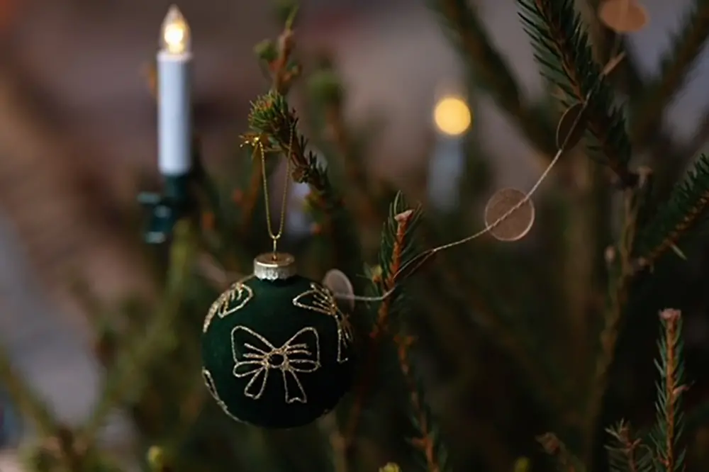 Detalj på en julgran. Julkula och belysning.